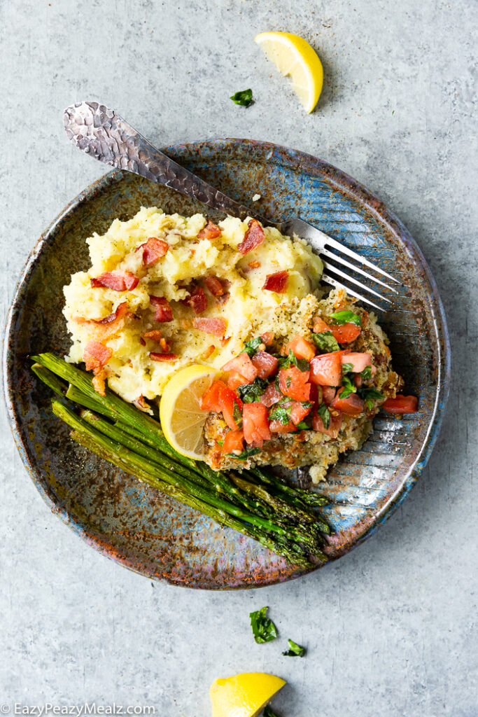 Bruschetta Chicken on a plate with mashed potatoes and asparagus