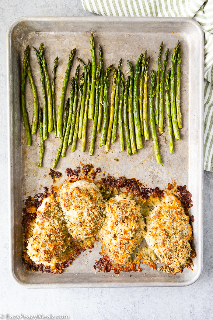 Mozzarella crusted chicken cutlets on a sheet pan with asparagus