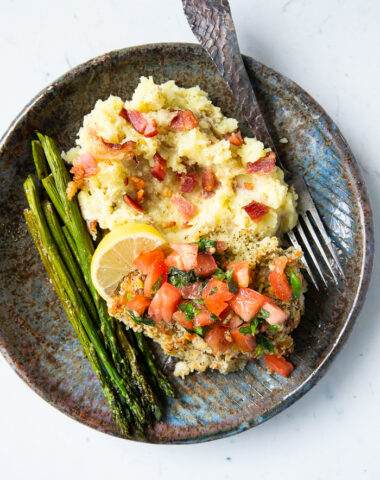 A plate with mashed potatoes, asparagus, and bruschetta chicken