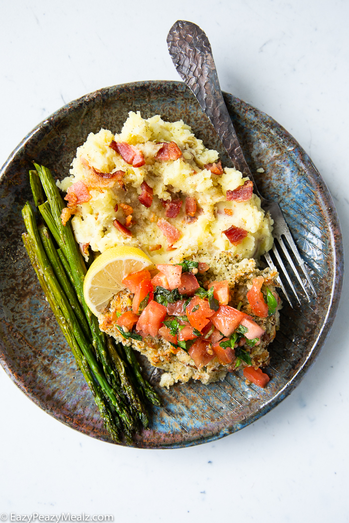 A plate with mashed potatoes, asparagus, and bruschetta chicken
