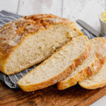 pieces of bread on a wooden cutting board with butter in the background