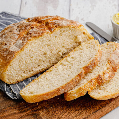 pieces of bread on a wooden cutting board with butter in the background