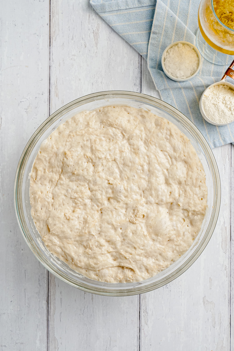 beer bread sitting out inn a glass bowl with ingredients to the side of the bowl