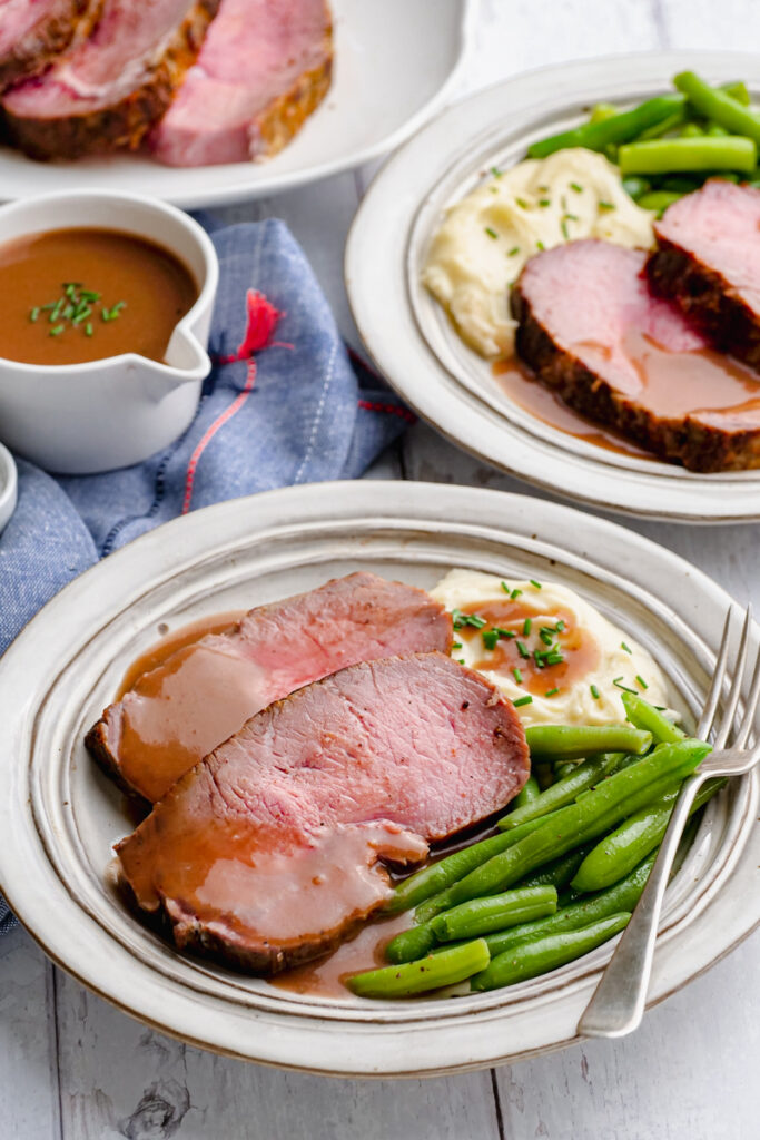 classic roast beef with gravy in the background
