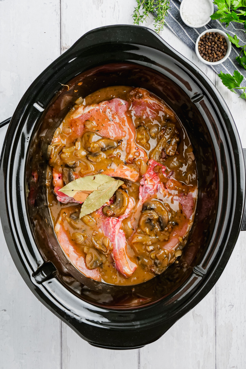 A slow cooker with pork chops and sauce