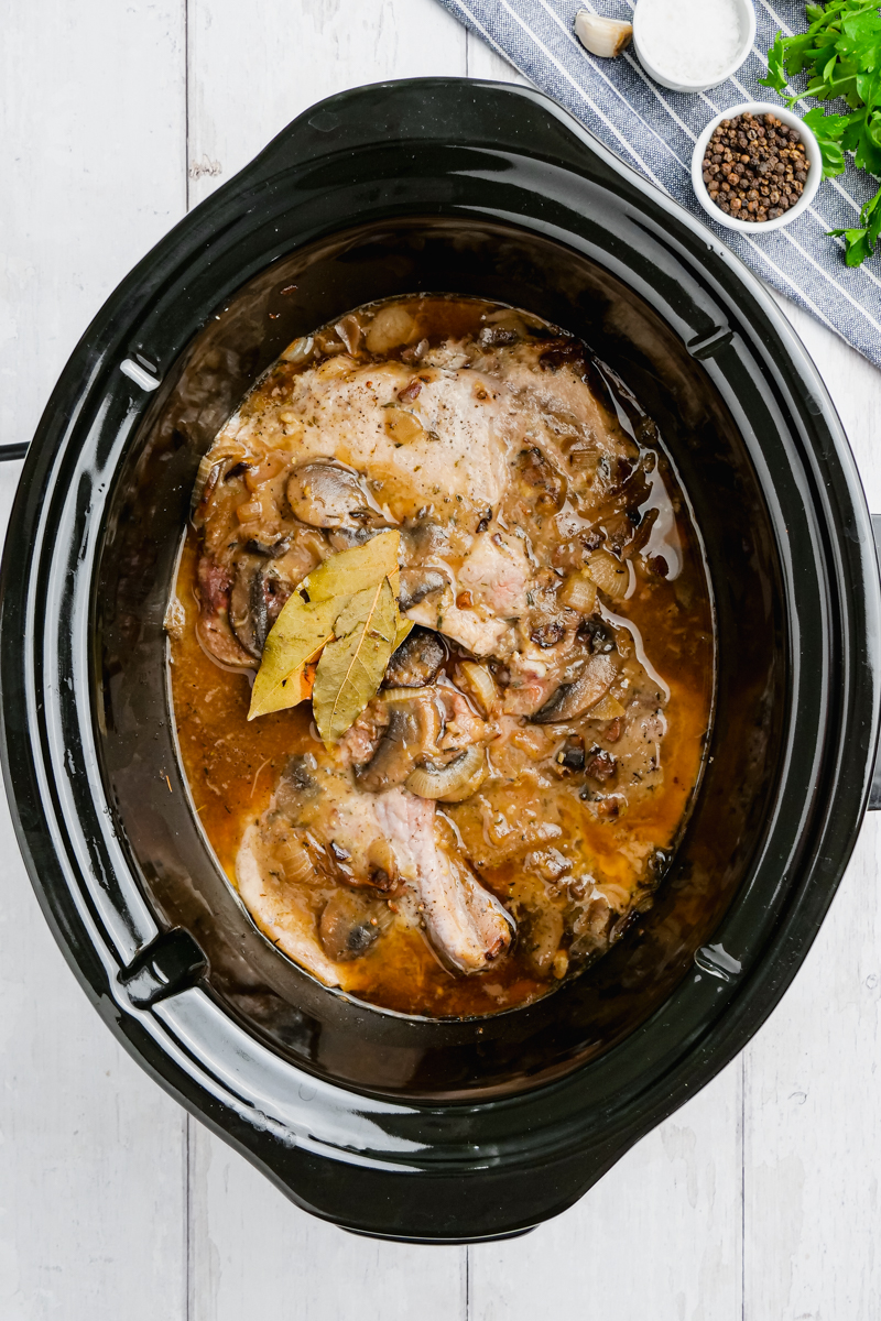 Cooked pork chops in a crock pot with mushroom sauce