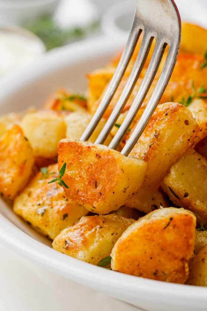 A fork poking into a crispy potato