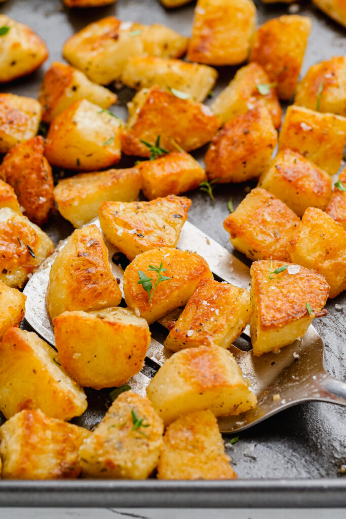 Crispy potatoes on a sheet pan with a metal spatula