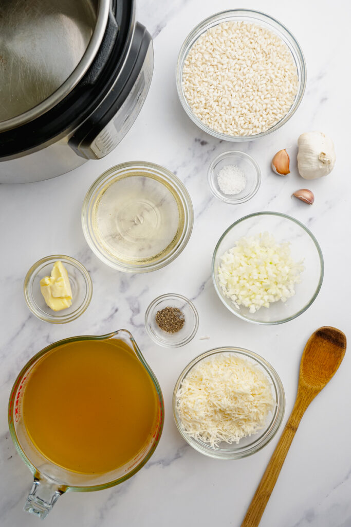 ingredients for parmesan risotto on counter with wooden spoon