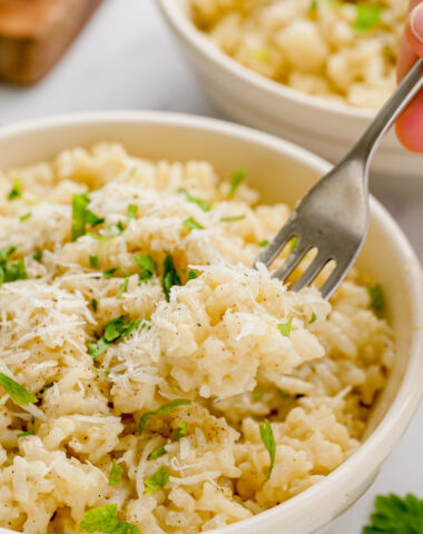 parmesan risotto in a white bowl with a fork