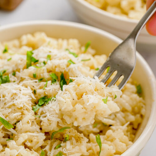 parmesan risotto in a white bowl with a fork