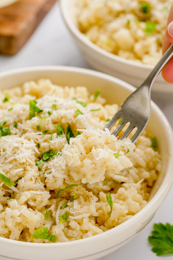 instant pot parmesan risotto in a white bowl with a fork