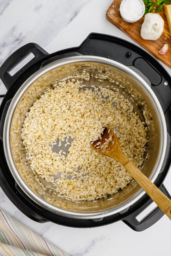 instant pot parmesan risotto in an instant pot with wooden spoon stirring