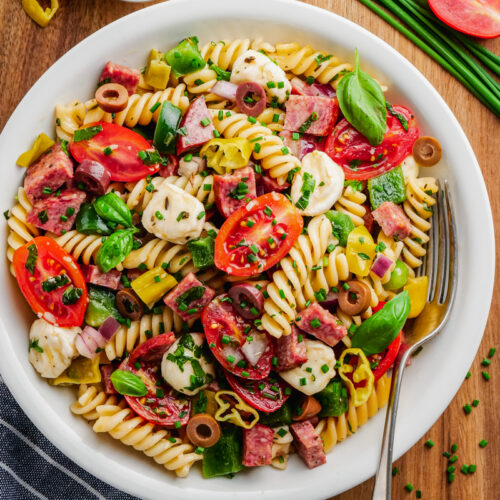 Italian pasta salad in white bowl with fork to the side