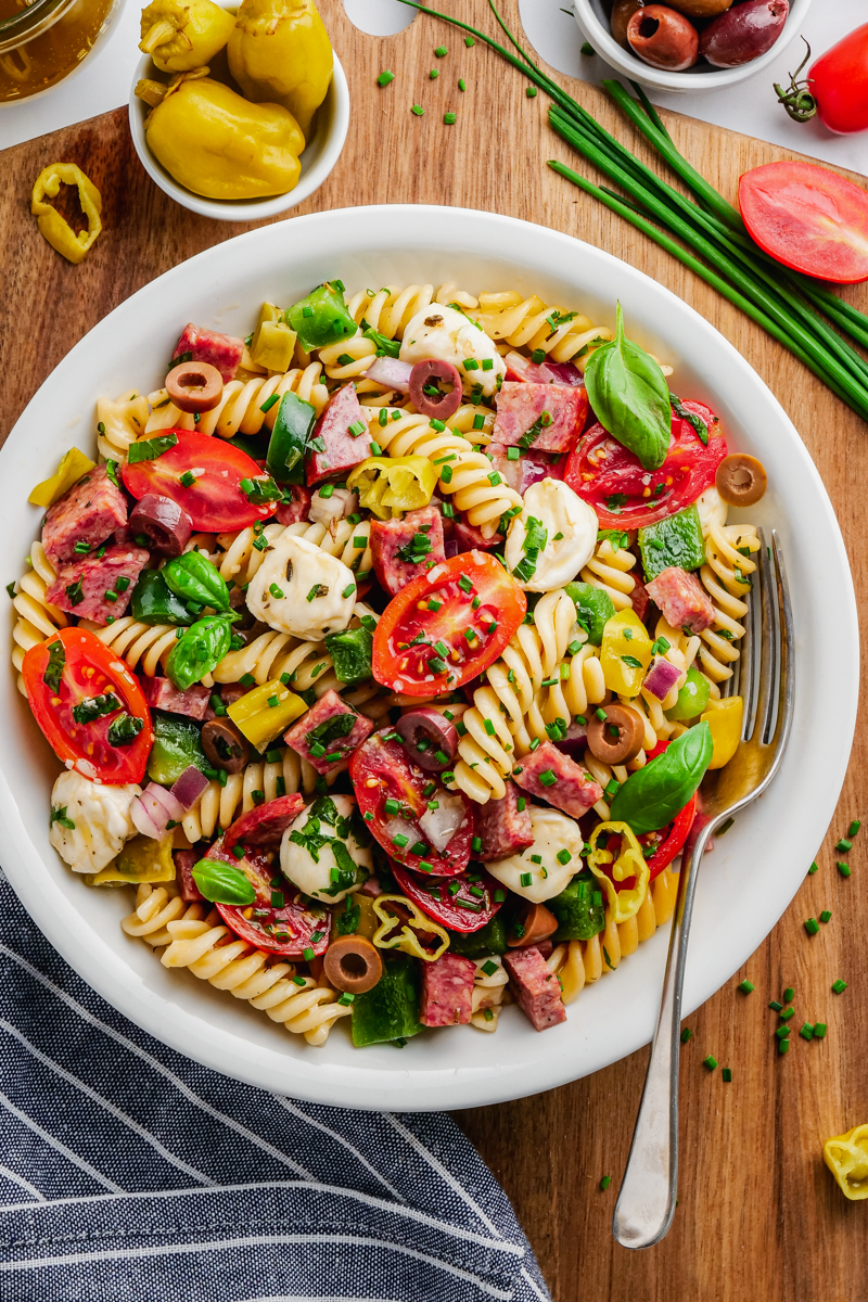 Italian pasta salad in white bowl with fork to the side