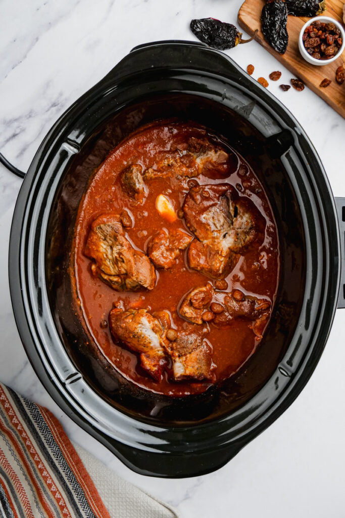 Cooked pork mole for pork tacos in a slow cooker