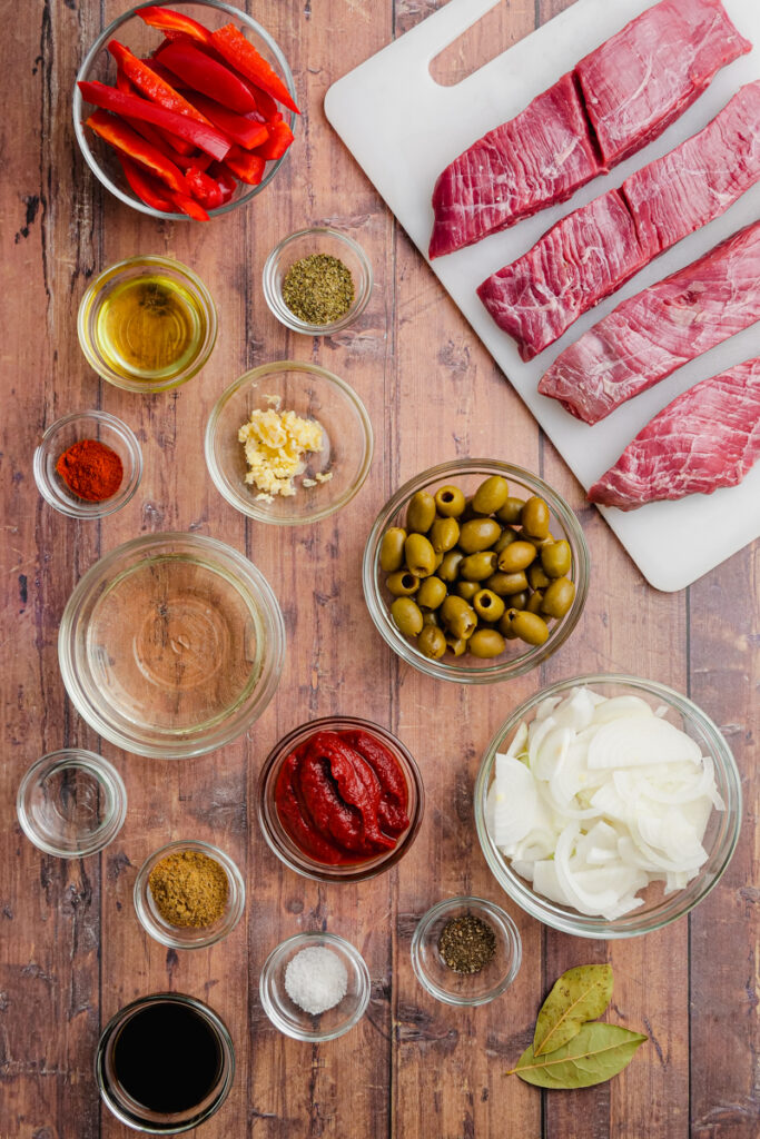 Small glass bowls, with all the ingredients for ropa vieja, on a wooden background