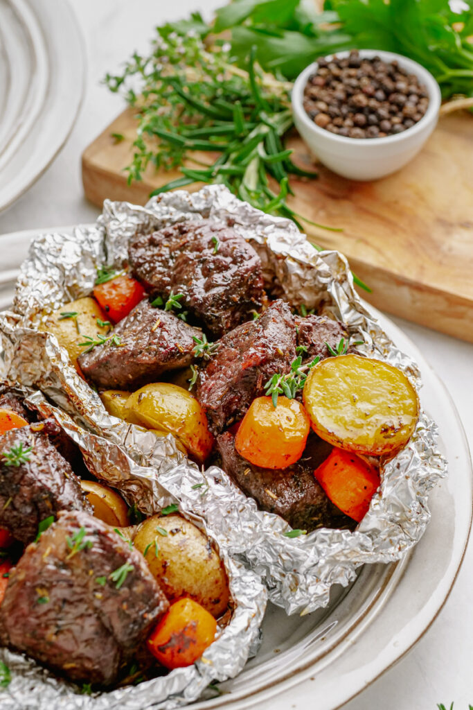 Foil packs of steak, potatoes, and carrots. 