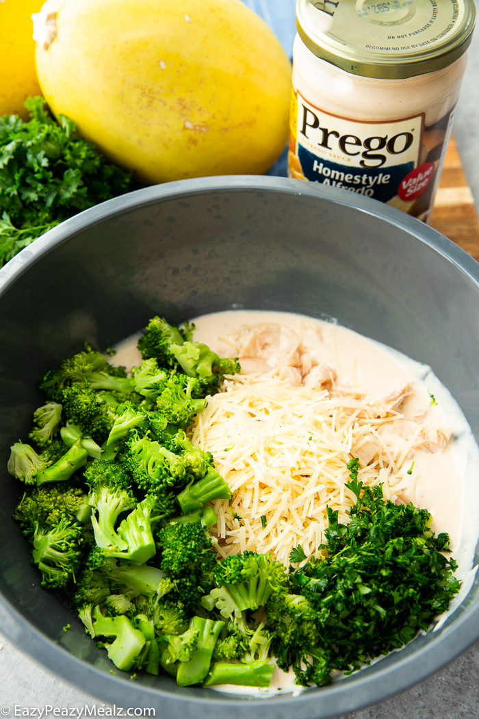 A gray bowl with the ingredients for spaghetti squash stuffed with broccoli chicken alfredo