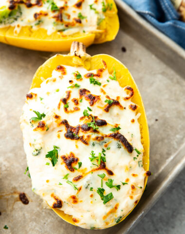 Broccoli chicken alfredo stuffed spaghetti squash on a baking sheet, garnished with parsley