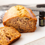 A loaf of banana bread that is sliced and doterra essential oil on the side.