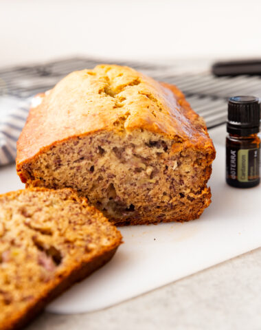 A loaf of banana bread that is sliced and doterra essential oil on the side.