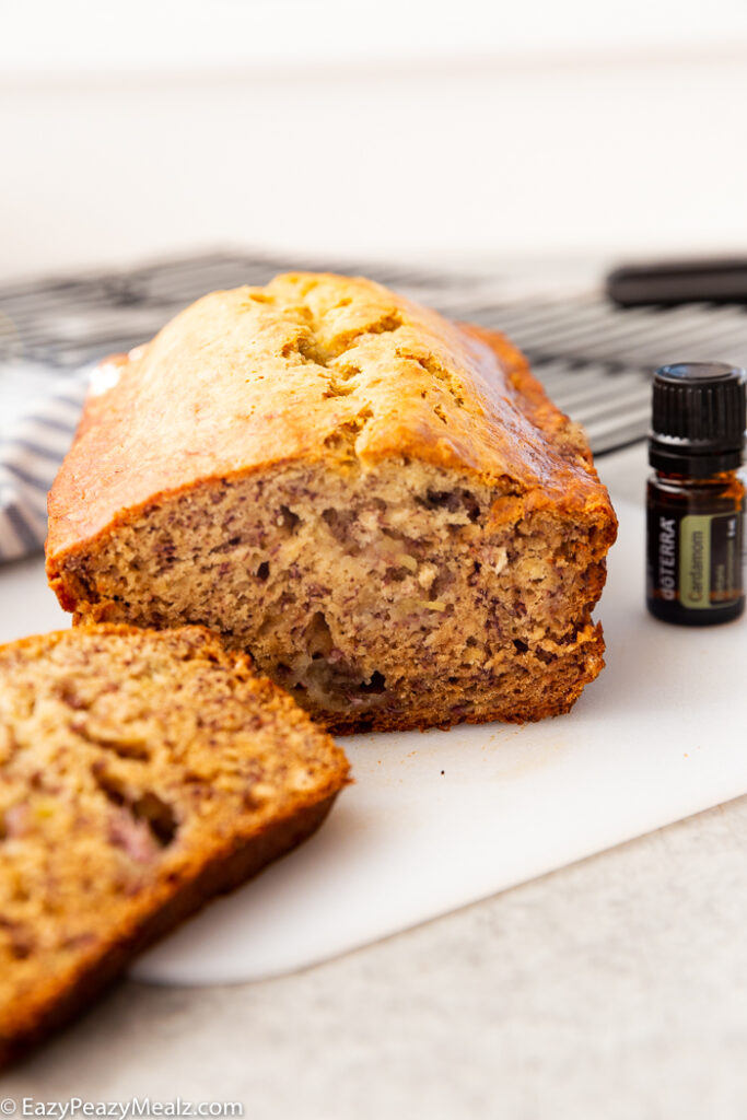 A loaf of banana bread that is sliced and doterra essential oil on the side. 