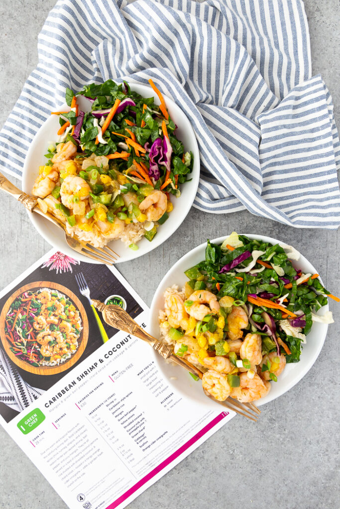 Caribbean shrimp and coconut rice on two plates with a green chef recipe card behind. 