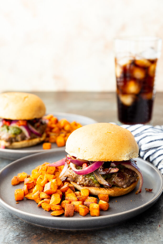 southwest fajita cheeseburger on grey plate with sweet potatoes to the side of the dish. 