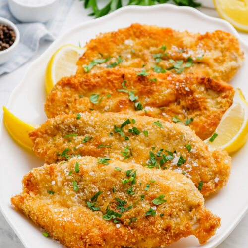 Breaded chicken cutlets on a white plate.