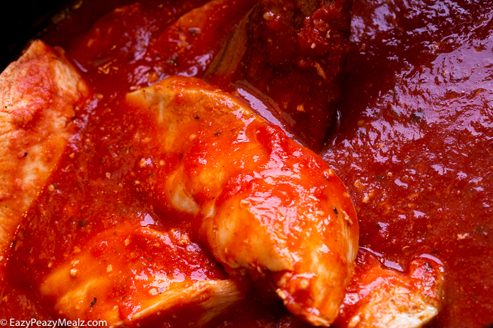 A crock pot full of chicken and sauce.