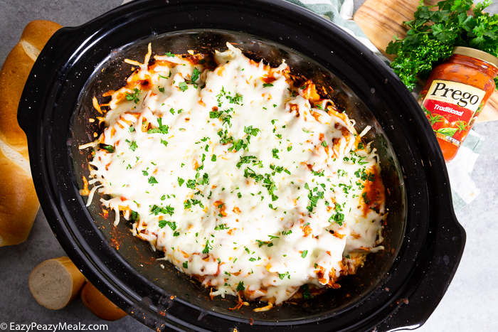 A slow cooker full of slow cooker chicken parmesan casserole, garnished with parsley.