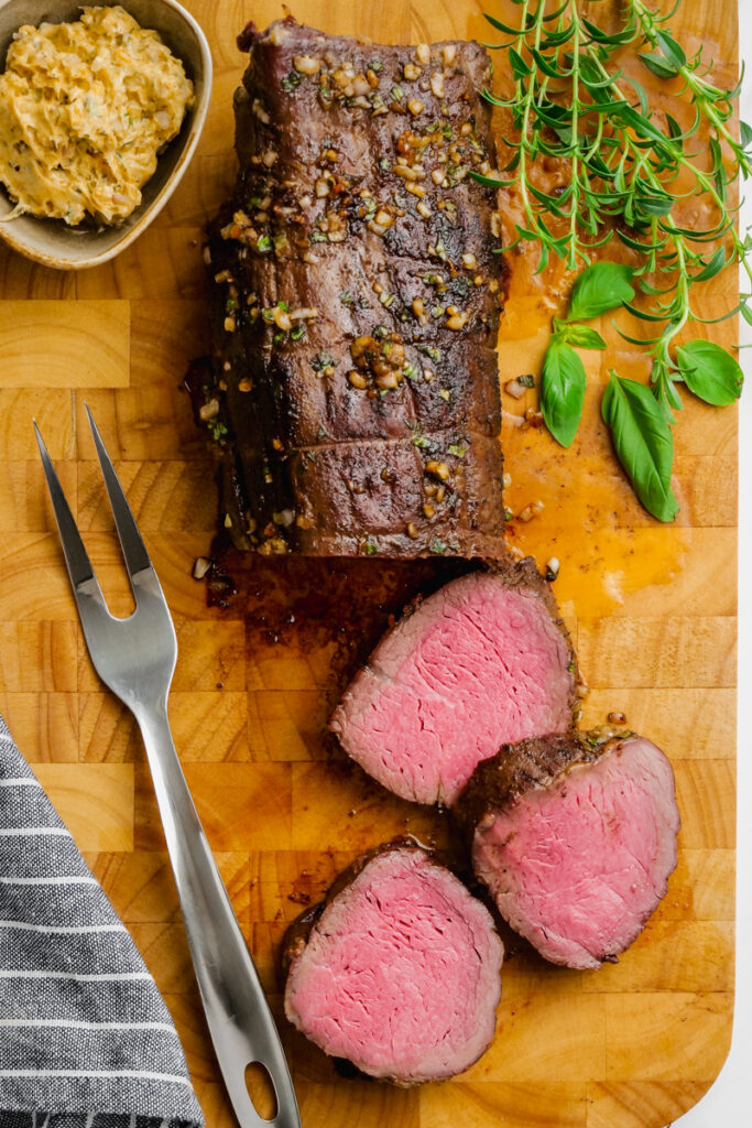 A half carved roast beef tenderloin on a cutting board