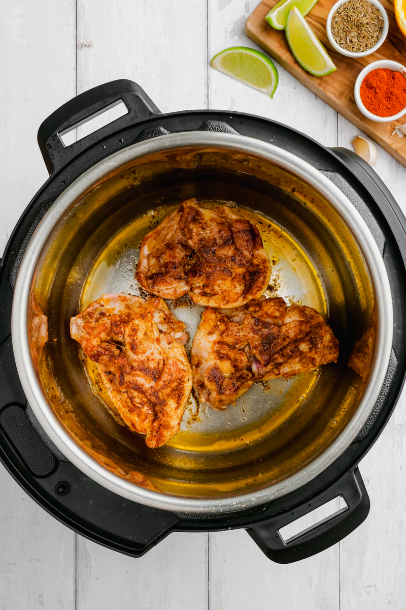 the chicken thighs being moved form skillet to slow cooker