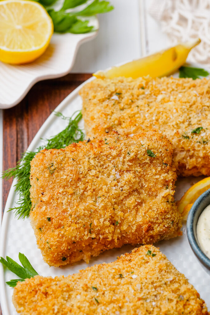 Oven fried fish on a white plate with garnish