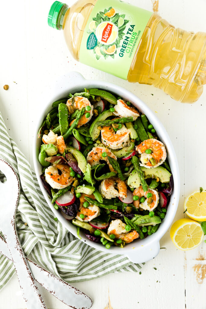 Citrus shrimp spring salad in a white bowl with lipton tea