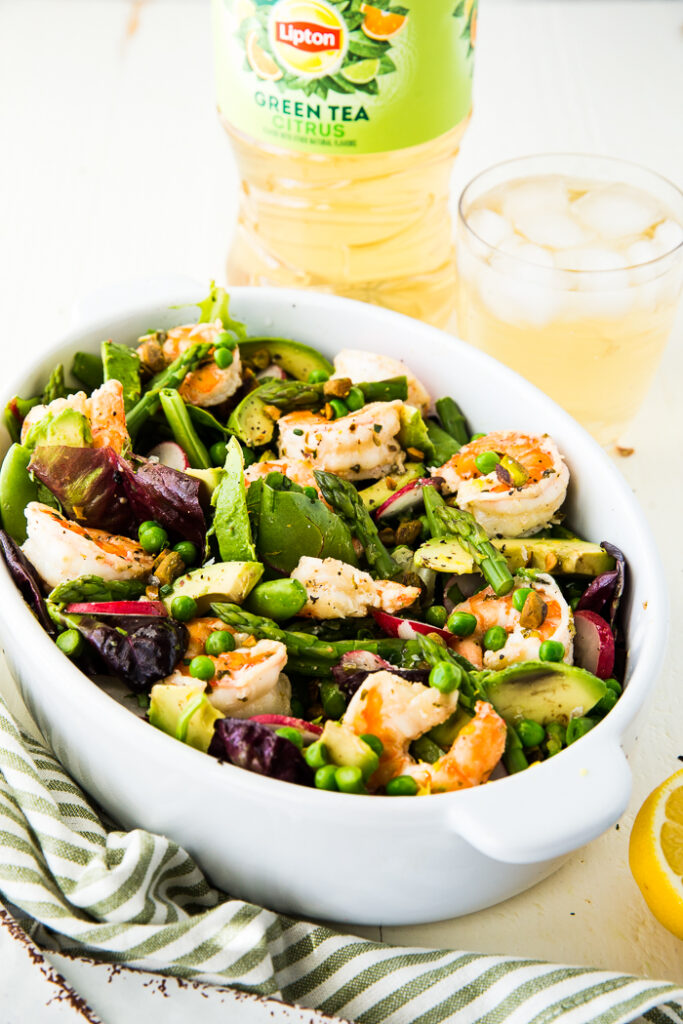 Citrus shrimp spring salad in a serving dish with iced tea