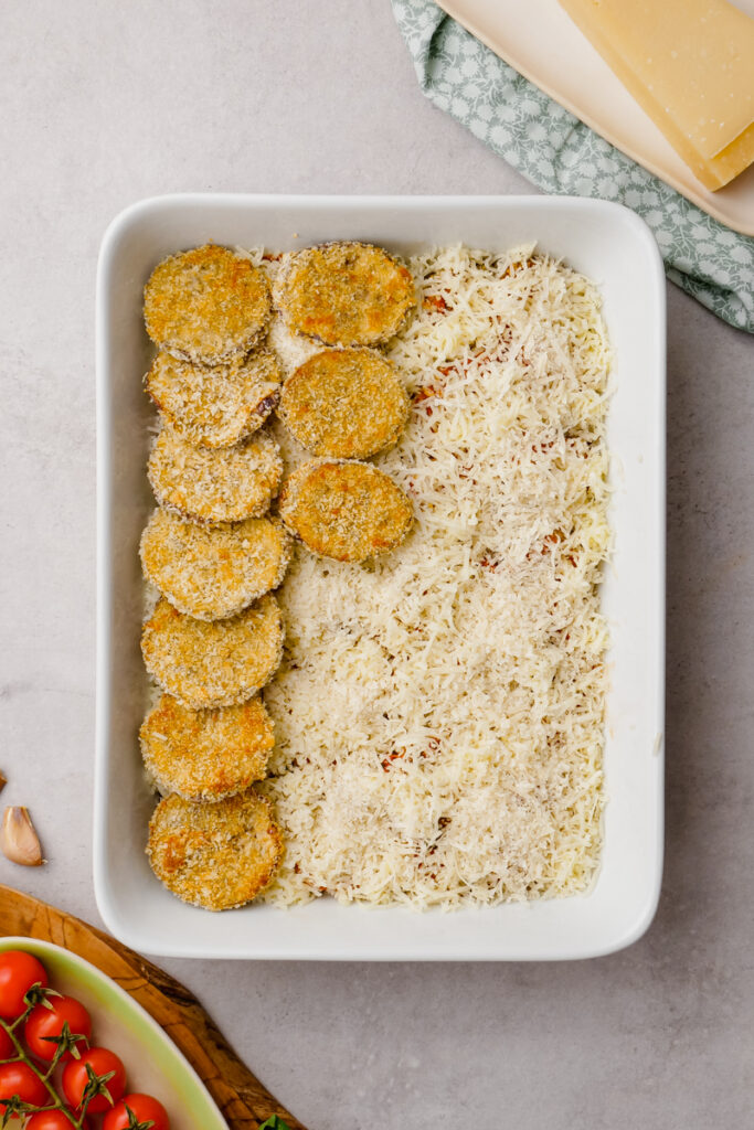 eggplant parmesan in parmesan cheese in a white glass container.