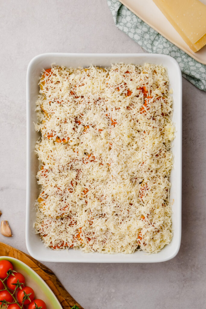 Layered eggplant parmesan in a white baking dish before going into the oven. 