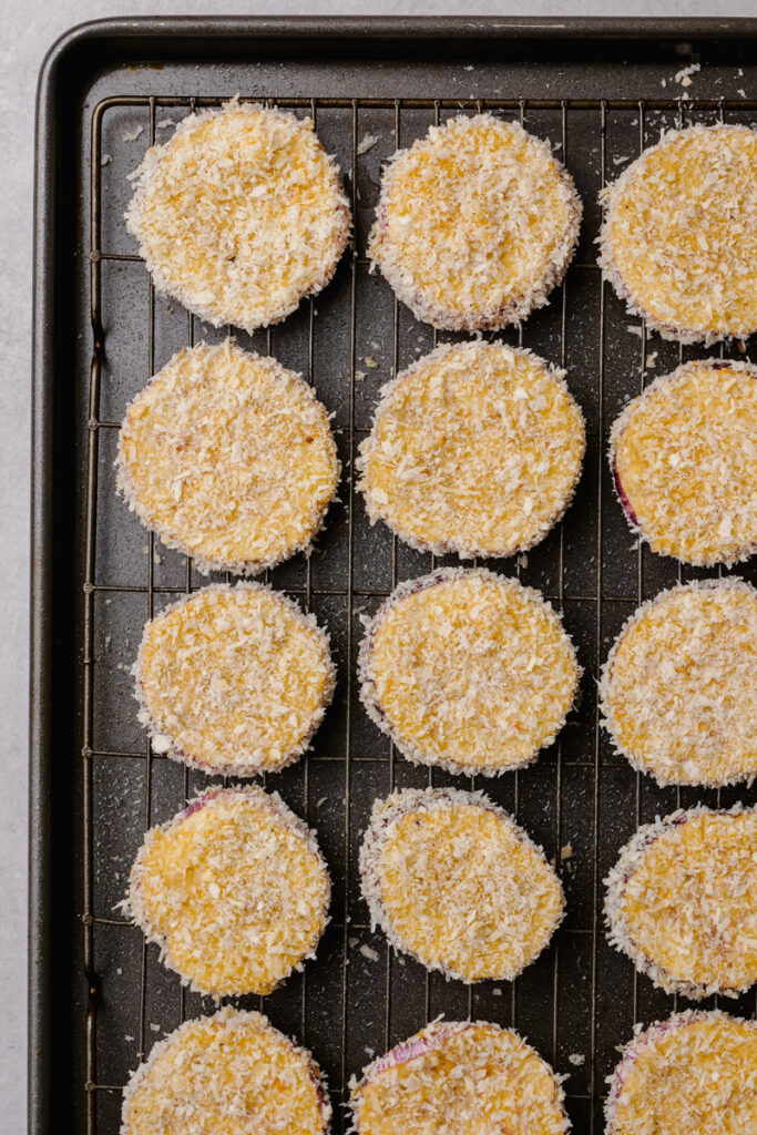 Dredged and coated eggplant rounds on a baking sheet