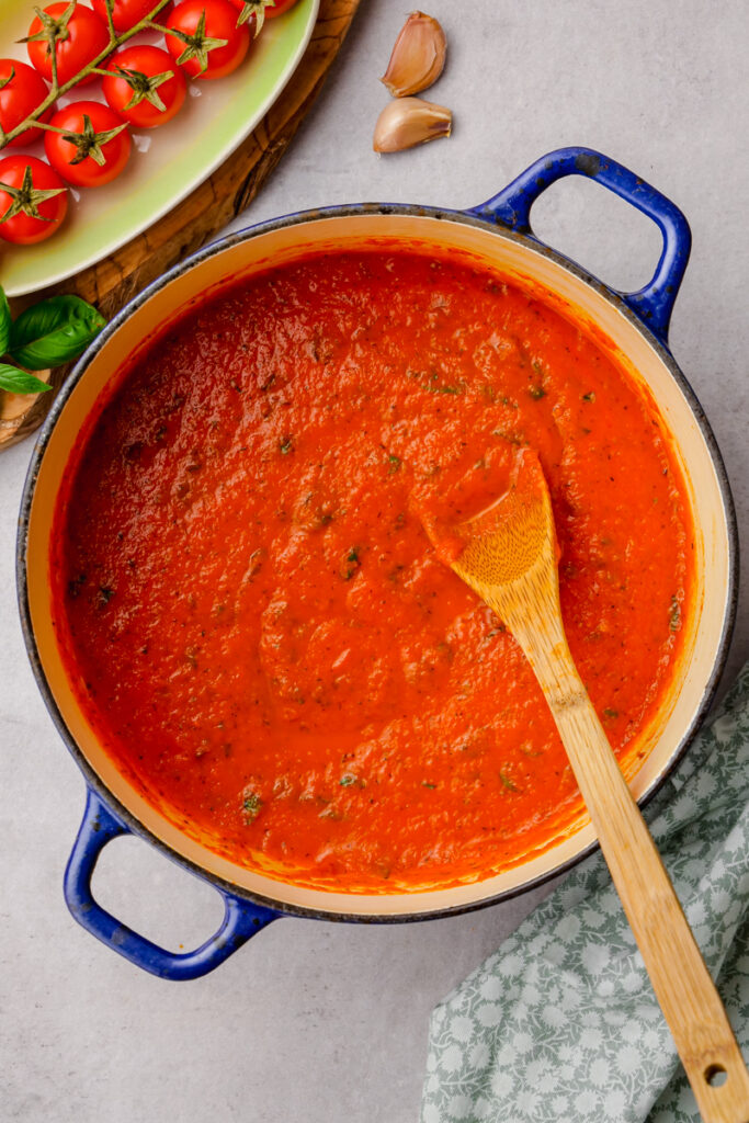 eggplant parmesan sauce in a blue bowl with tomatoes on the side