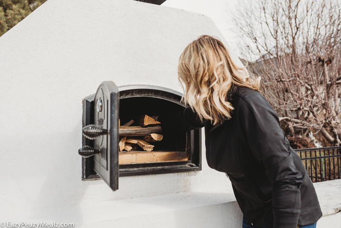 Putting wood in a wood fired oven to start it. 