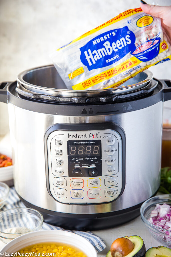 An instant pot with a bag of dry beans being put into it.