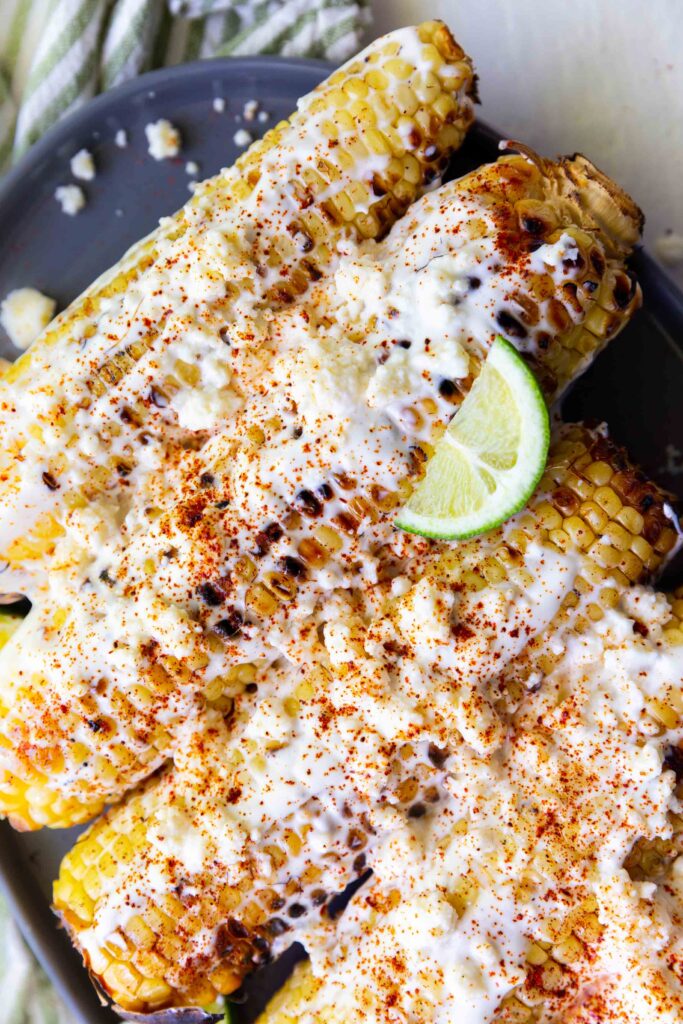 A plate of elote, or mexican street corn, with cotija and lime