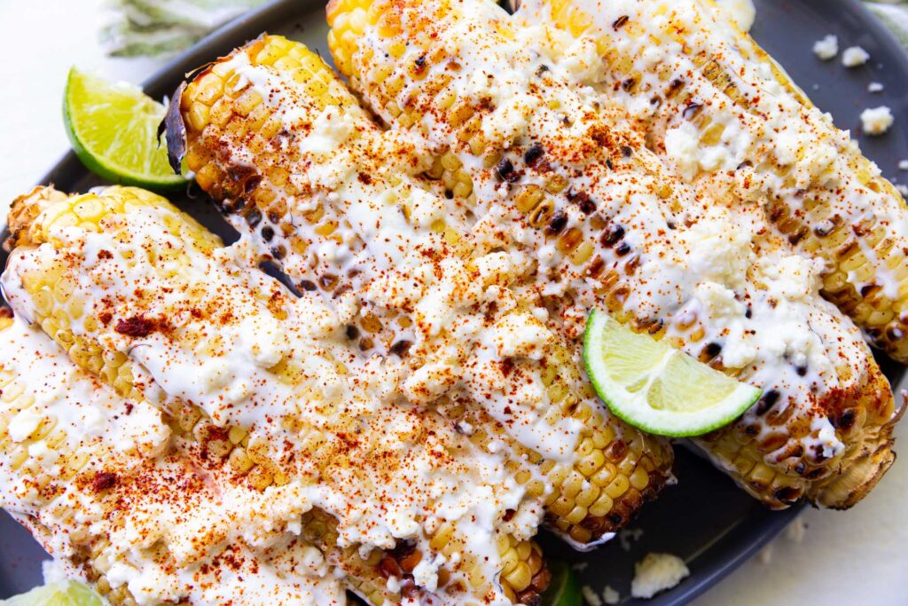 Top corn with sauce and cheese for elote