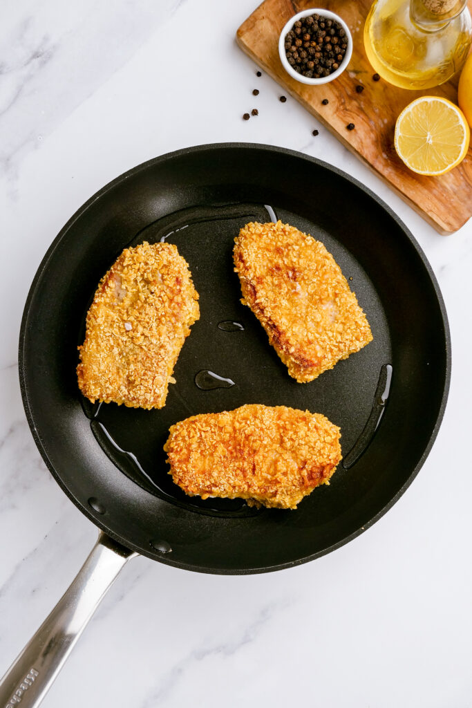 Breaded pork chops being pan fried