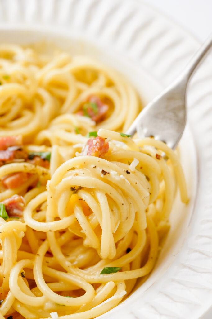 Carbonara, a fantastic pasta dish, in a white plate, and a fork. 
