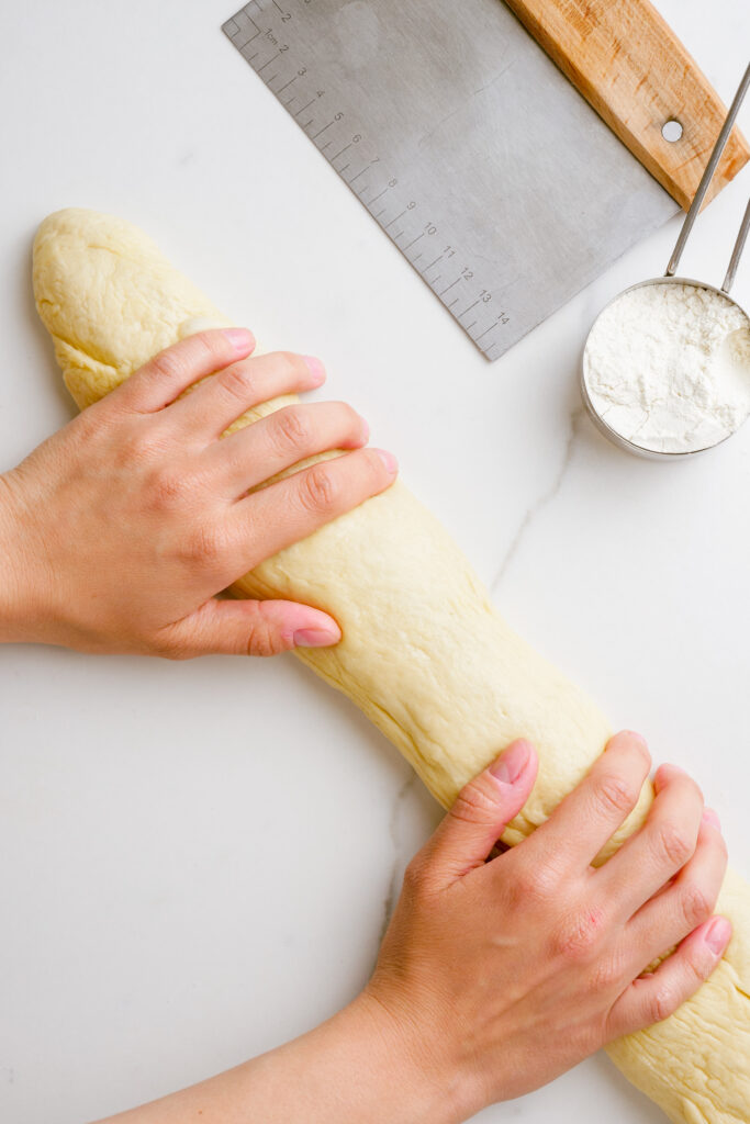 Kneading parker house roll dough on a counter top surface. 