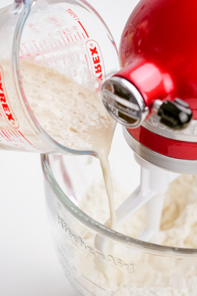 Combining the wet and dry ingredients in a mixer to make Parker House Rolls