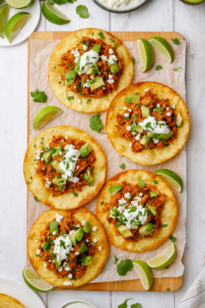 Platter of tinga tostadas, loaded with braised pork and a crispy tortilla